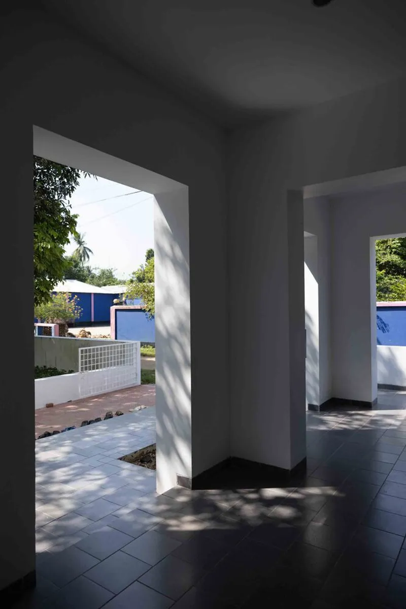 Covered entry space with dark floor tiles opening to courtyard framed by trees