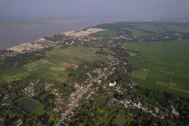 Aerial perspective showing residential clusters between cultivated green fields and a river estuary