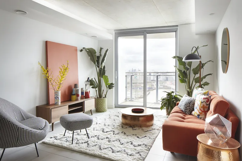 Interior living room with floor-to-ceiling windows overlooking the cityscape and potted plants