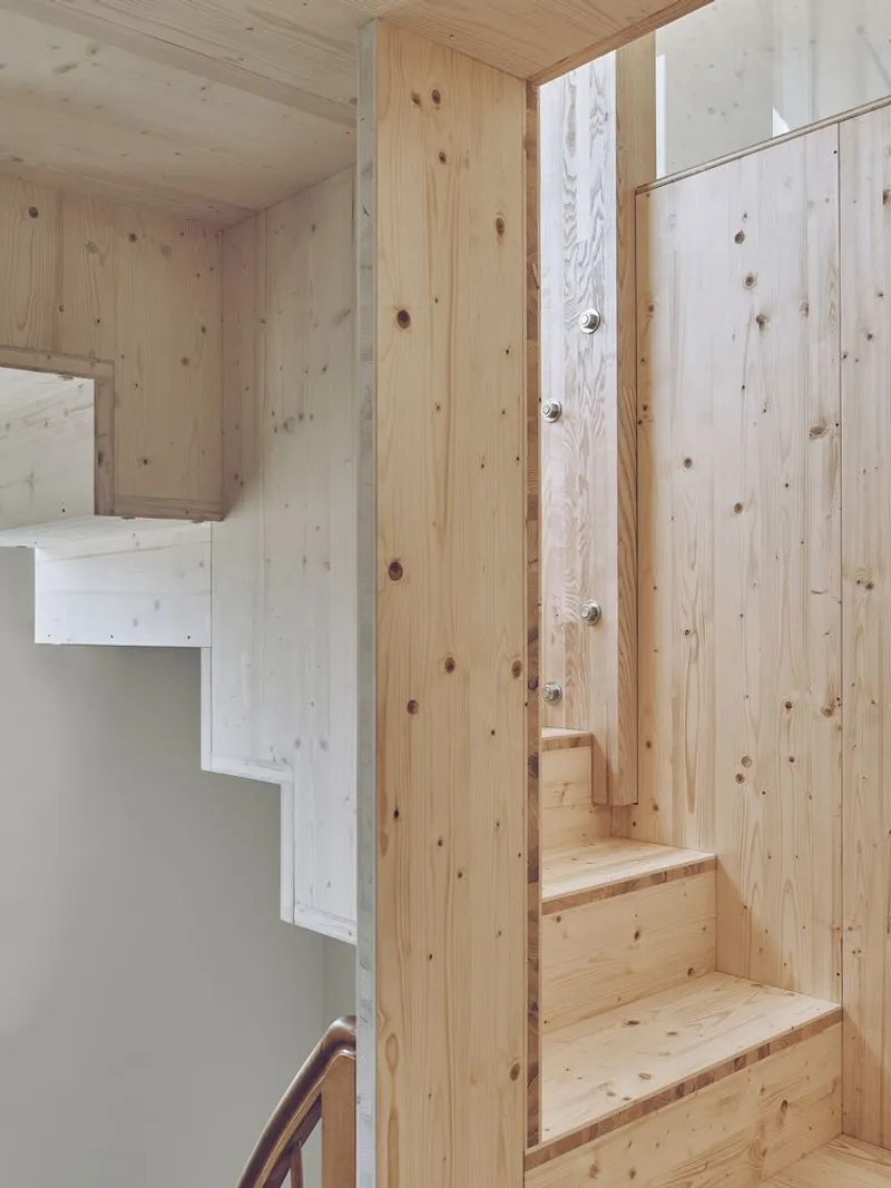 Compact timber staircase with exposed wood grain and integrated handrail between plywood walls