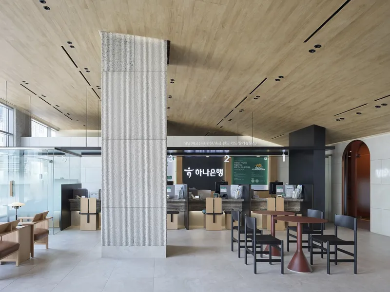 Banking hall with vertical ribbed column and timber ceiling above scattered seating