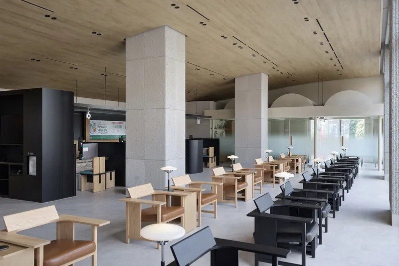Interior seating area with concrete columns, wood ceiling and rows of black display units