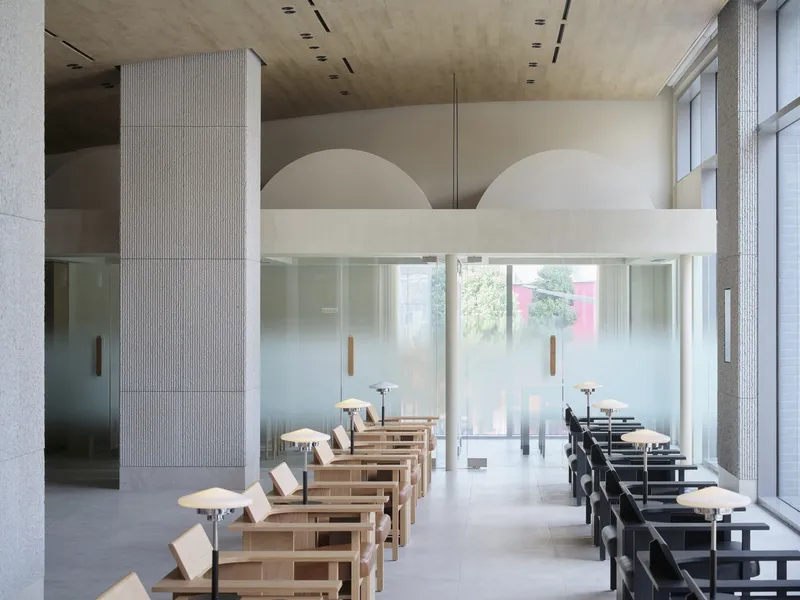 Textured concrete columns and arched alcoves above translucent glass partitions in a daylit interior