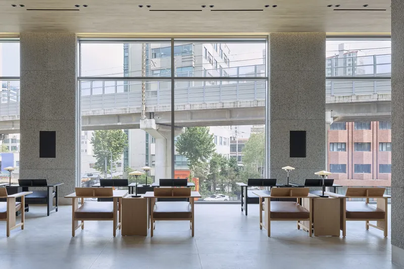 Symmetrical seating arrangement with concrete columns framing a view of an elevated pedestrian bridge outside