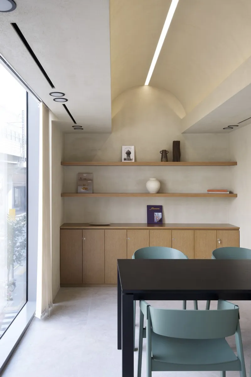 Dining area with timber shelving and vaulted ceiling lit by a recessed linear slot