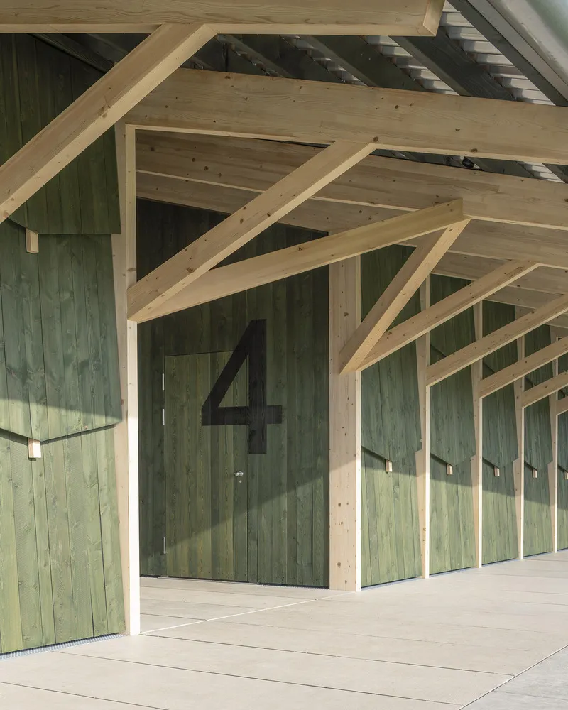 Green-stained timber doors beneath exposed timber rafters with numbered panels and metal hooks