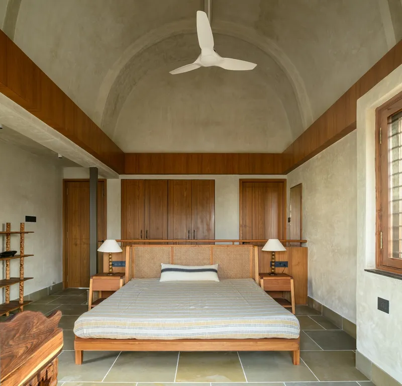 Bedroom with barrel-vaulted ceiling, wood paneling, cane headboard, and a ceiling fan