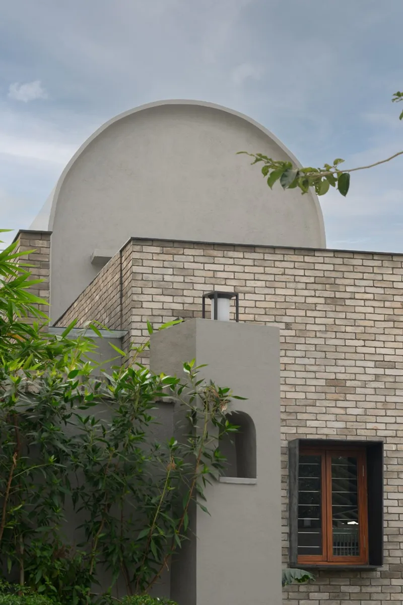 Facade detail showing a curved stucco vault rising above brick wall and timber window opening