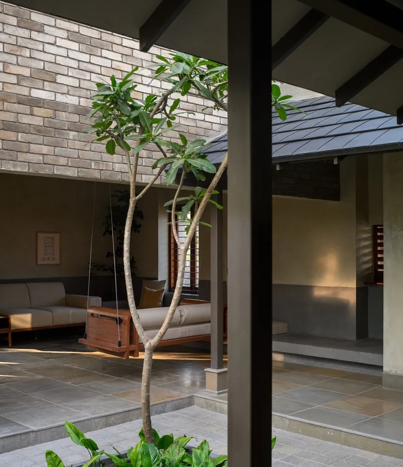 View through steel column toward courtyard tree and seating areas illuminated by natural light