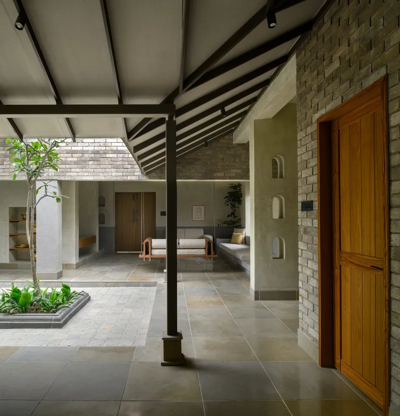 Interior courtyard with steel columns, exposed rafters, brick walls, and tree growing from floor