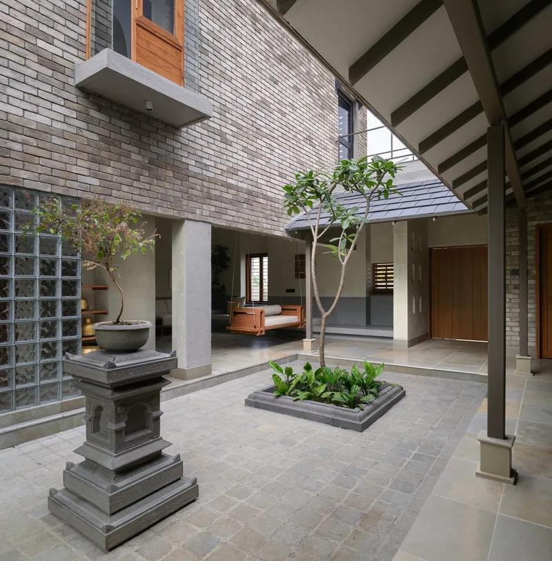 Interior courtyard with white brick walls, stone pavers, planted trees and glass block screen