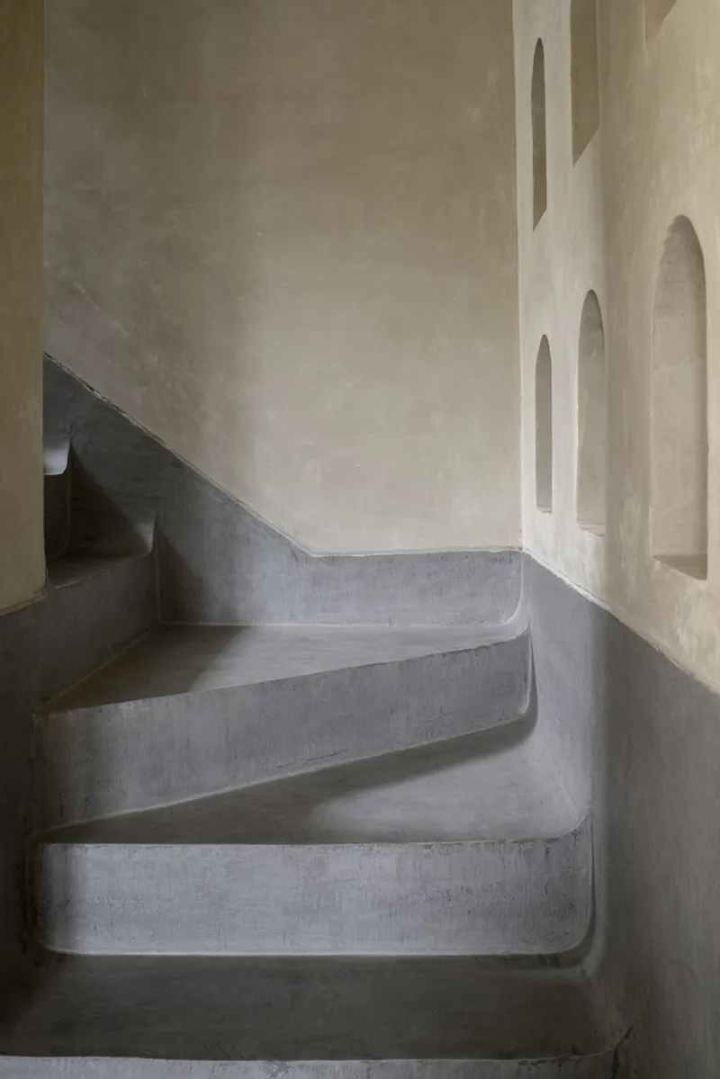 Curved concrete staircase with arched wall niches and soft afternoon light