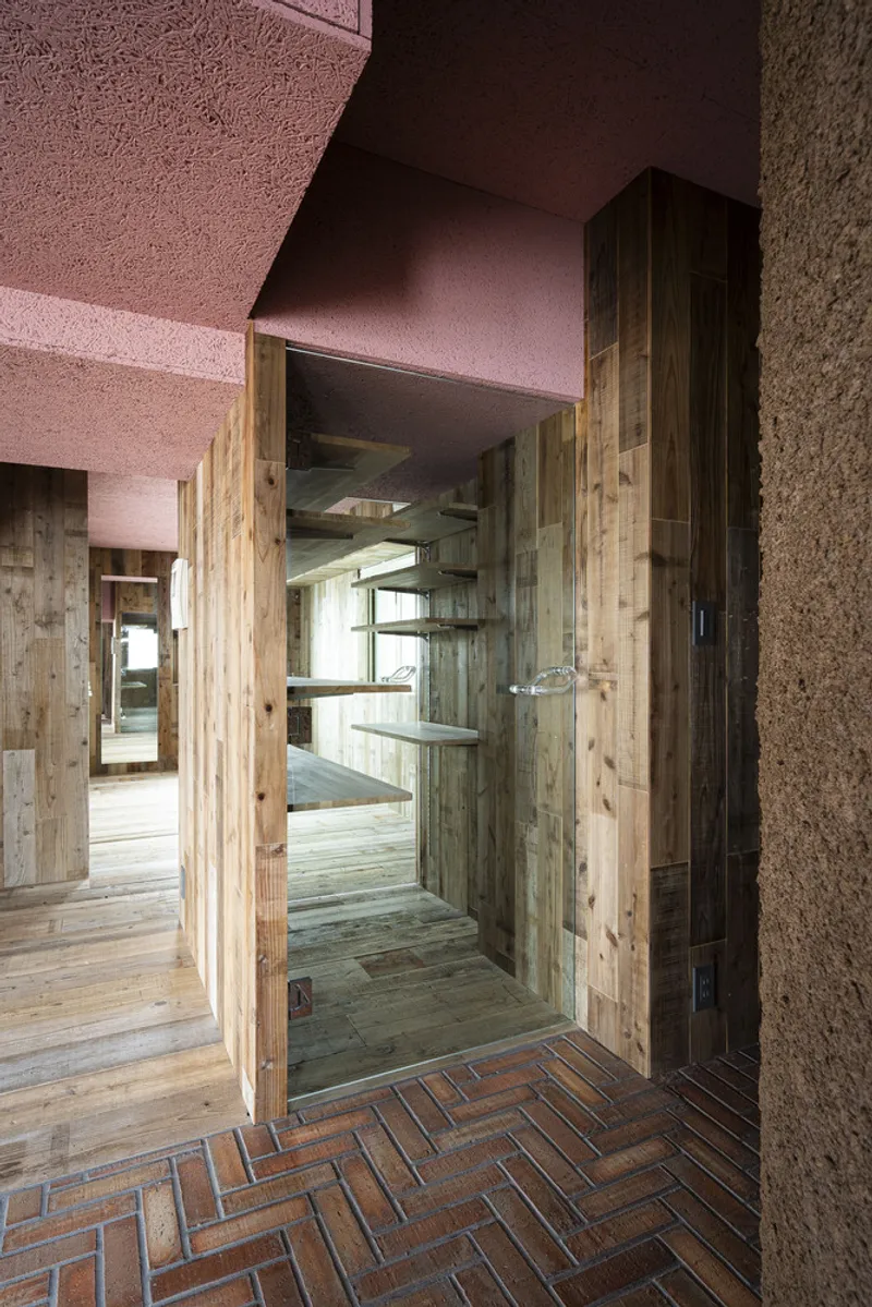 Timber-framed doorway opening onto herringbone brick floor with pink ceiling above