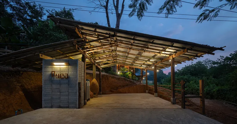 Open-air covered terrace with translucent roof panels and exposed timber frame at dusk