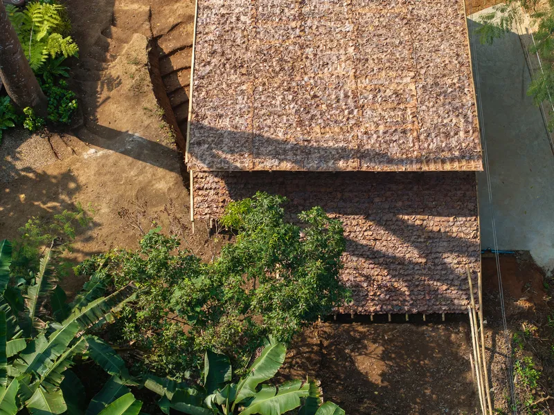 Aerial view of thatched roof pavilion surrounded by planted beds and bare soil