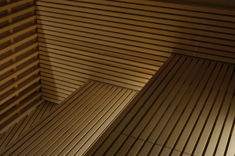 Close-up of horizontal timber slat benches in a sauna with concealed linear lighting