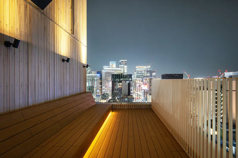 Rooftop terrace with timber decking and vertical slat screening overlooking the illuminated city skyline at dusk