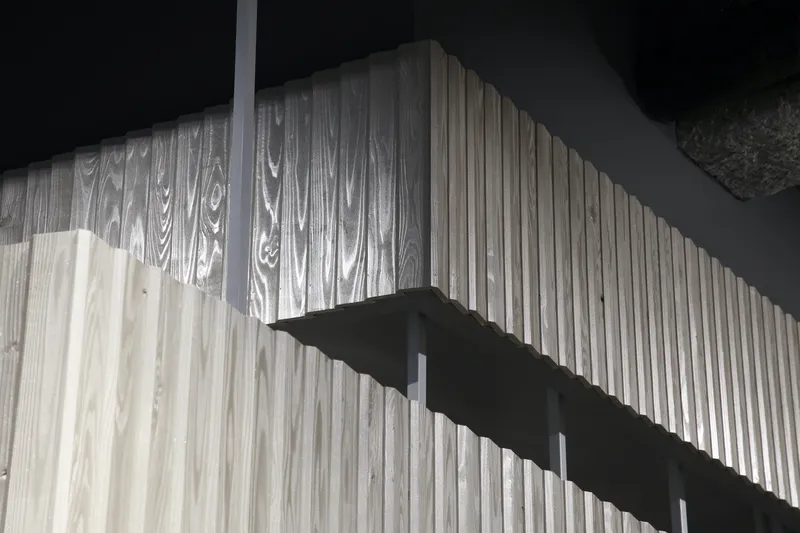 Vertical timber slat wall illuminated by dramatic shadows cast from an overhead cantilevered element