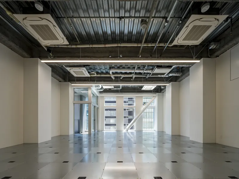 Open-plan interior with exposed corrugated metal ceiling, ceiling cassettes, and polished concrete floor