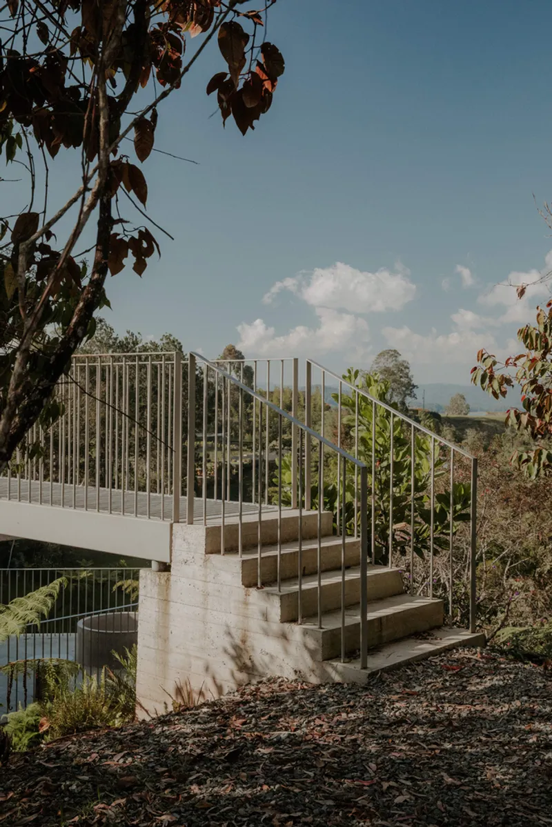 Exterior staircase with vertical metal balustrade and concrete base ascending through garden planting