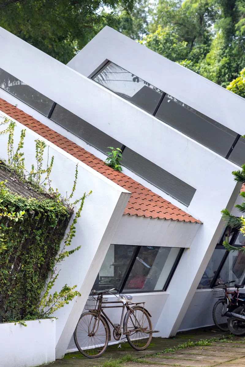 White angled facade with clerestory window and terracotta tile peeking through folded roof planes