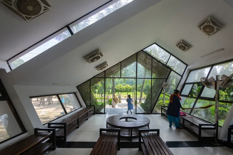 Interior view with polished concrete floor and timber furniture beneath angled skylights and glass walls