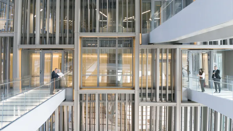 Interior atrium showing open office floors with glass balustrades and people working at multiple levels