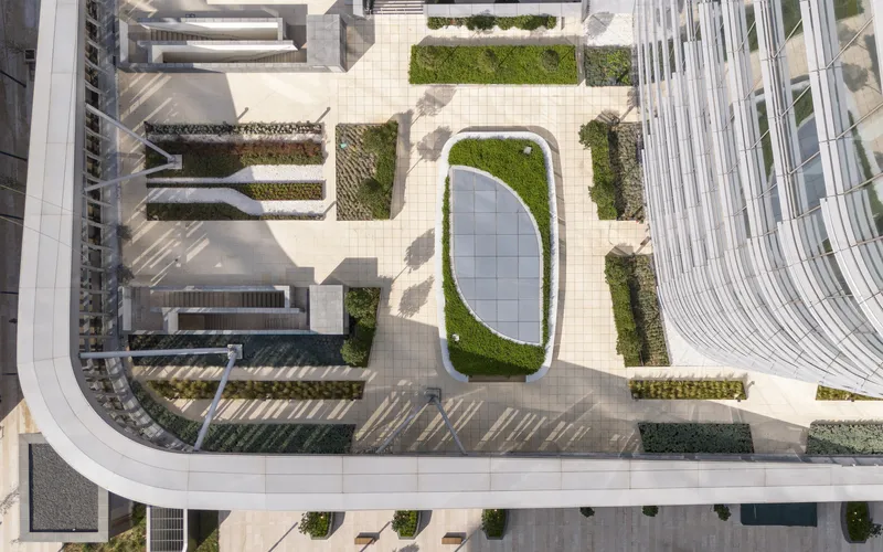 Aerial view of a rooftop terrace with an oval skylight surrounded by green planted beds