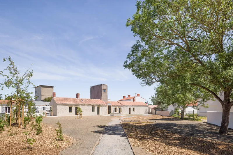Courtyard view of the single-story white-walled building with terracotta tile roof under a blue sky