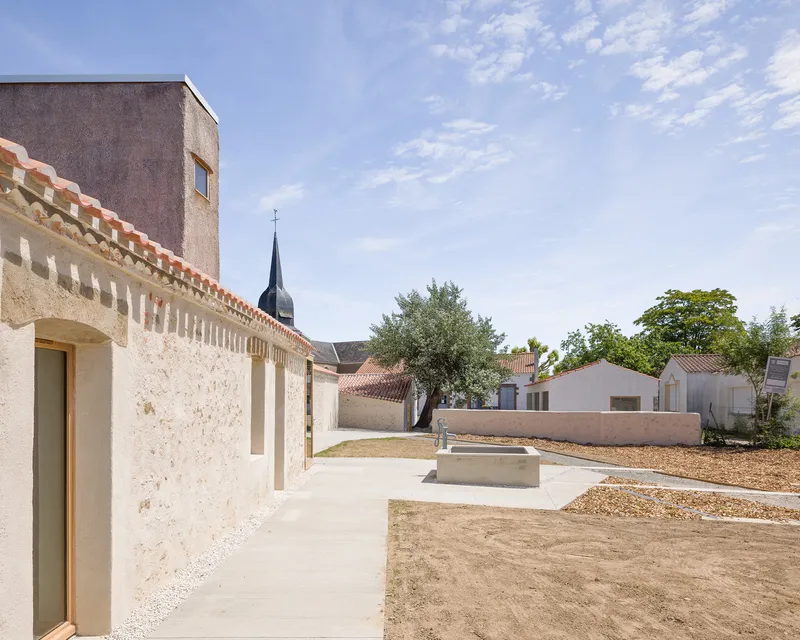Concrete pathway alongside the crenellated stone wall with church spire visible in the distance