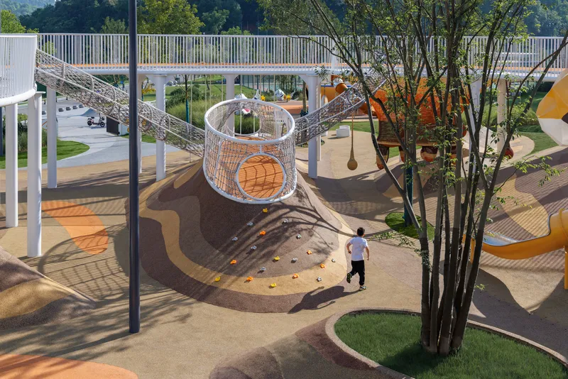 Elevated playground with woven mesh tunnel slide and white columns beside a child walking across patterned ground