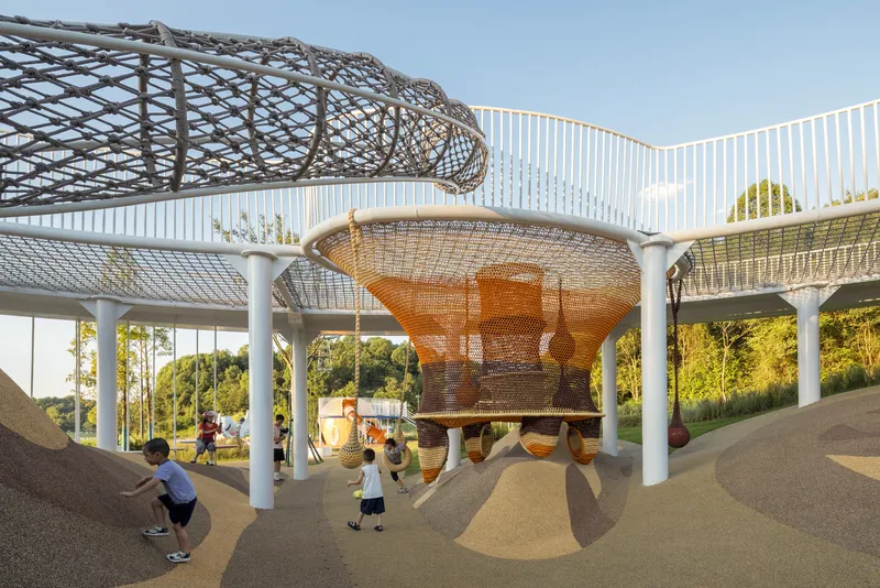 Layered mesh canopies and platforms supported by white columns with children playing beneath in afternoon light