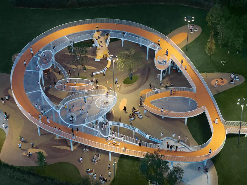 Aerial view of the looping playground structure with orange pathways and white railings in evening light