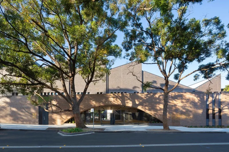 Street view of the brick facade beneath mature eucalyptus trees casting dappled shadows
