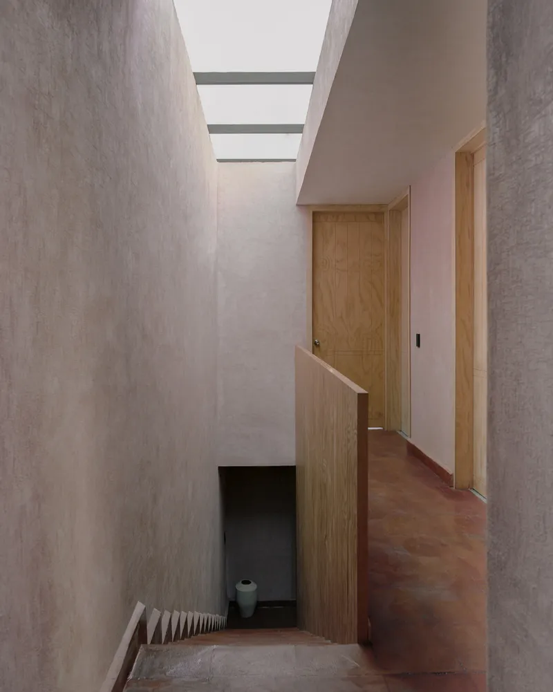 Stairwell with clerestory skylight above timber handrail and doorway leading to corridor