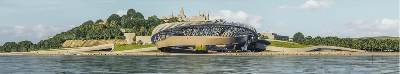 Distant view of the ribbed shell structure on the waterfront with historic buildings on the hill behind