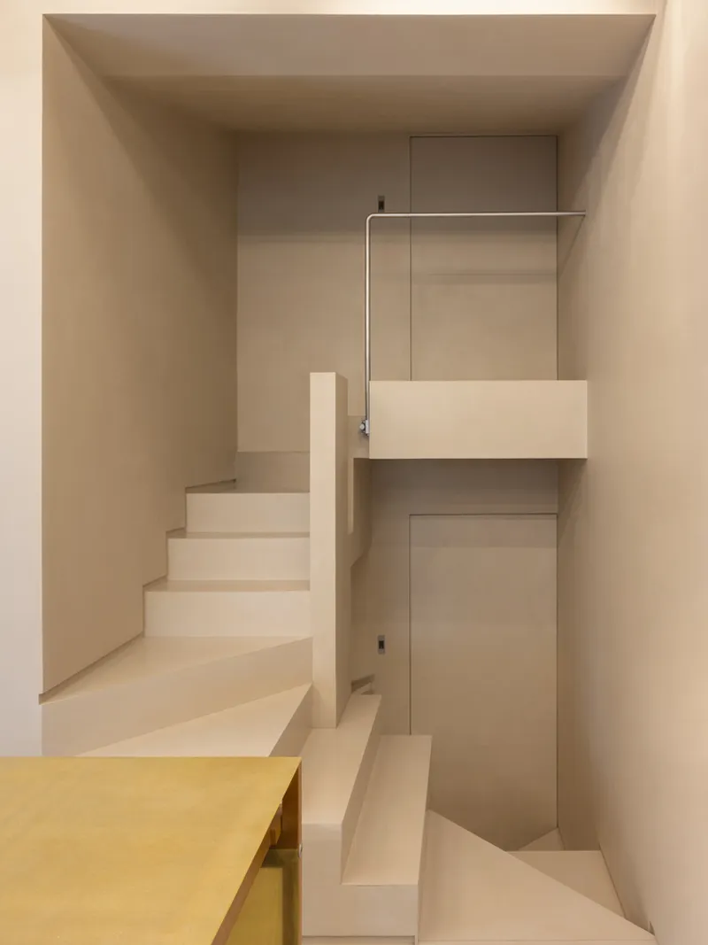 Plaster stairwell with ascending and descending runs flanking a yellow partition wall