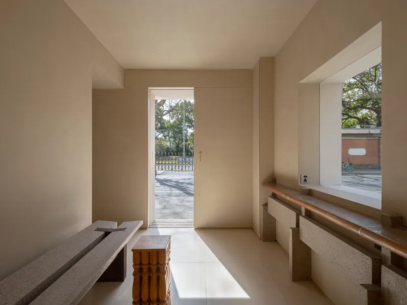 Entry room with terrazzo bench and timber stool facing a glazed door opening to the street