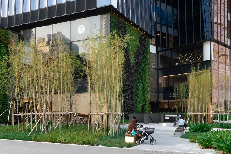 Ground-level plaza with bamboo groves in planters and a parent pushing a stroller