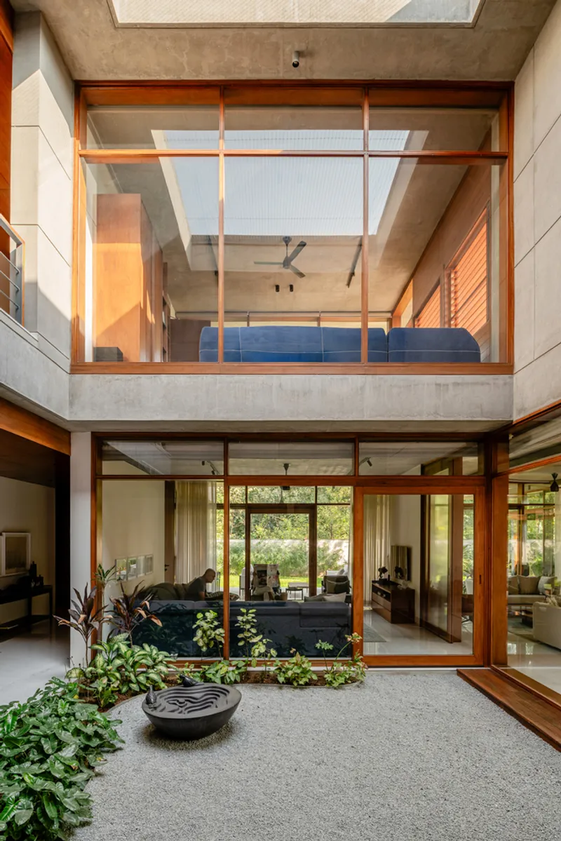 Internal courtyard with timber-framed glazing on two levels and potted plants on terrazzo flooring