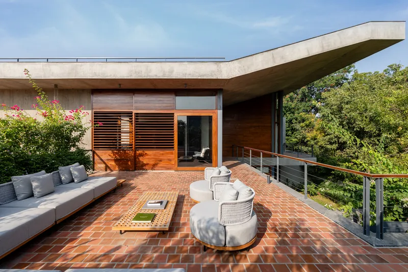 Roof terrace with herringbone clay tile paving, outdoor seating, and cantilevered concrete overhang