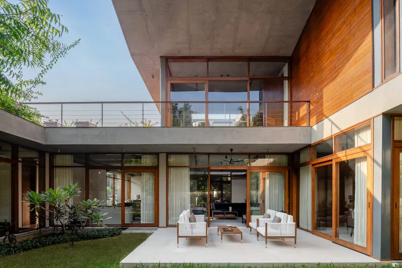 Private courtyard with lawn, seating area, and floor-to-ceiling timber-framed sliding glass doors