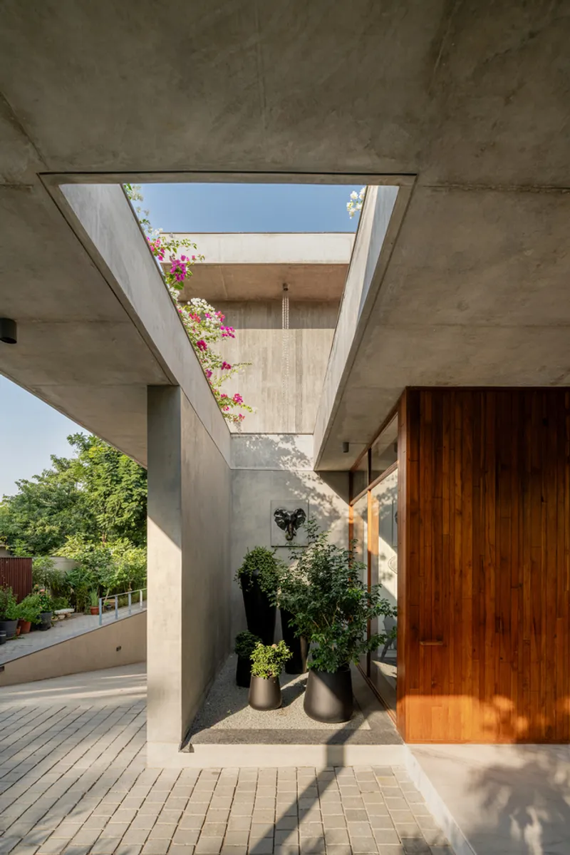 Covered entrance passage with exposed concrete vault, brick paving, planted beds and bougainvillea overhead