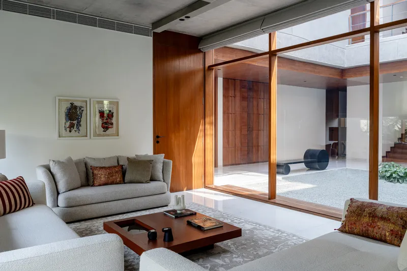 Living room with pivoting timber-framed glass doors opening to interior courtyard and sunlight streaming in