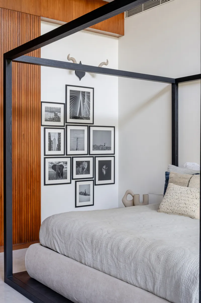 Bedroom corner with black steel bed canopy and vertical timber slat wall paneling