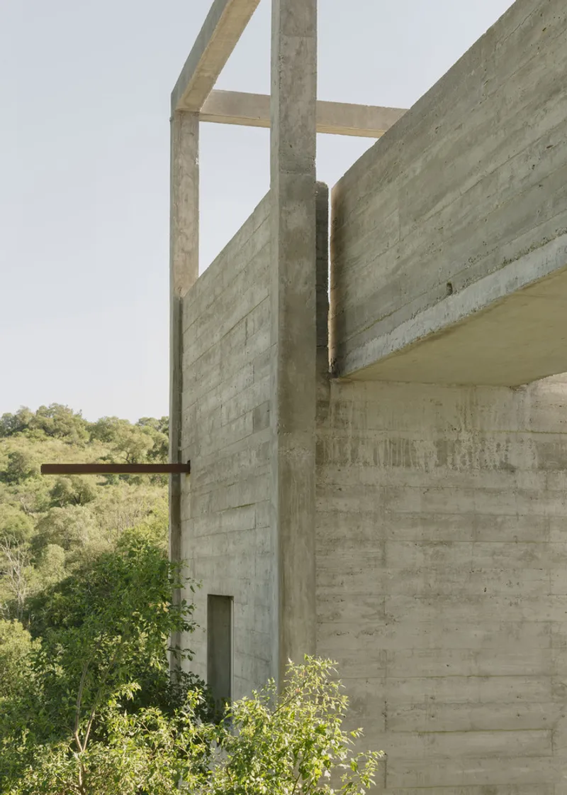 Corner detail of board-formed concrete wall meeting column with horizontal formwork pattern visible
