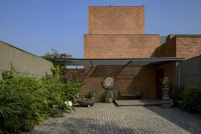 Brick courtyard with paver floor and horizontal wood screen under a corrugated metal canopy