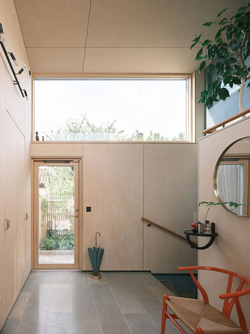 Entry hall with plywood paneling, clerestory window, and glazed door opening to a garden terrace