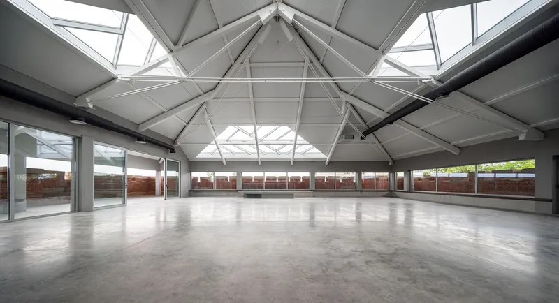 Interior hall with polished concrete floor and faceted ceiling structure with triangular skylights