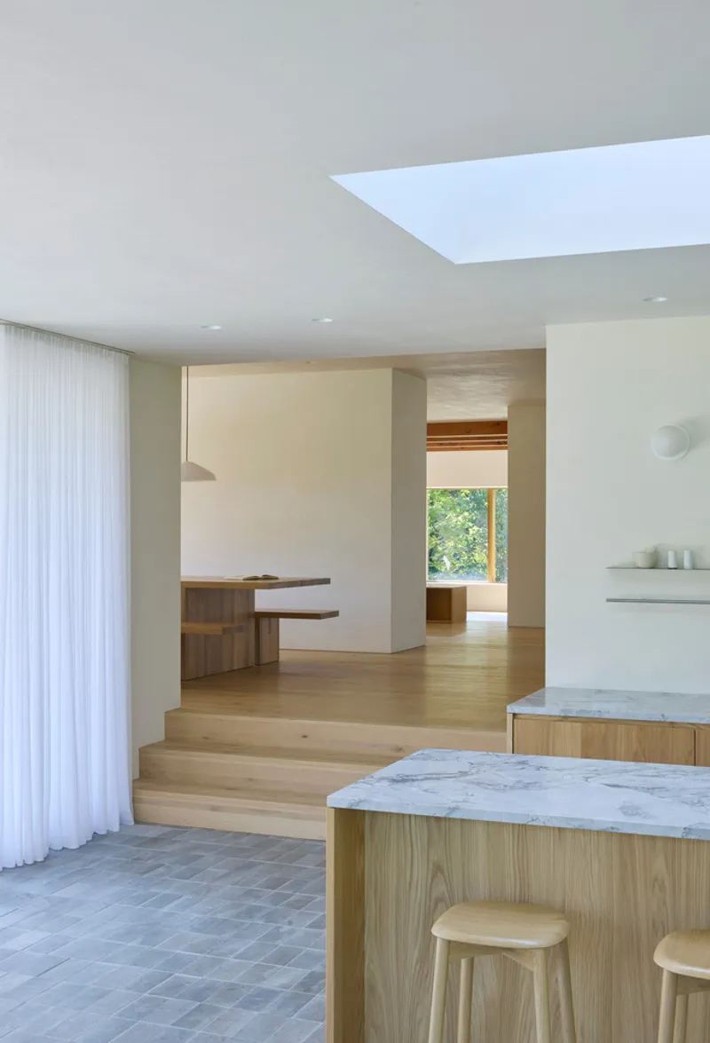 Kitchen and dining space with marble topped islands, timber joinery and linear skylight above